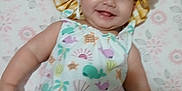 Daisy is registered to the contest to win money with this photo: baby, smiling, hat, sun_hat, swimsuit, colorful_clothing, lying_down, floral_pattern, blanket, infant, child, cute, happy, face, cheeks, skin, indoors, one_person, portrait, baby_girl