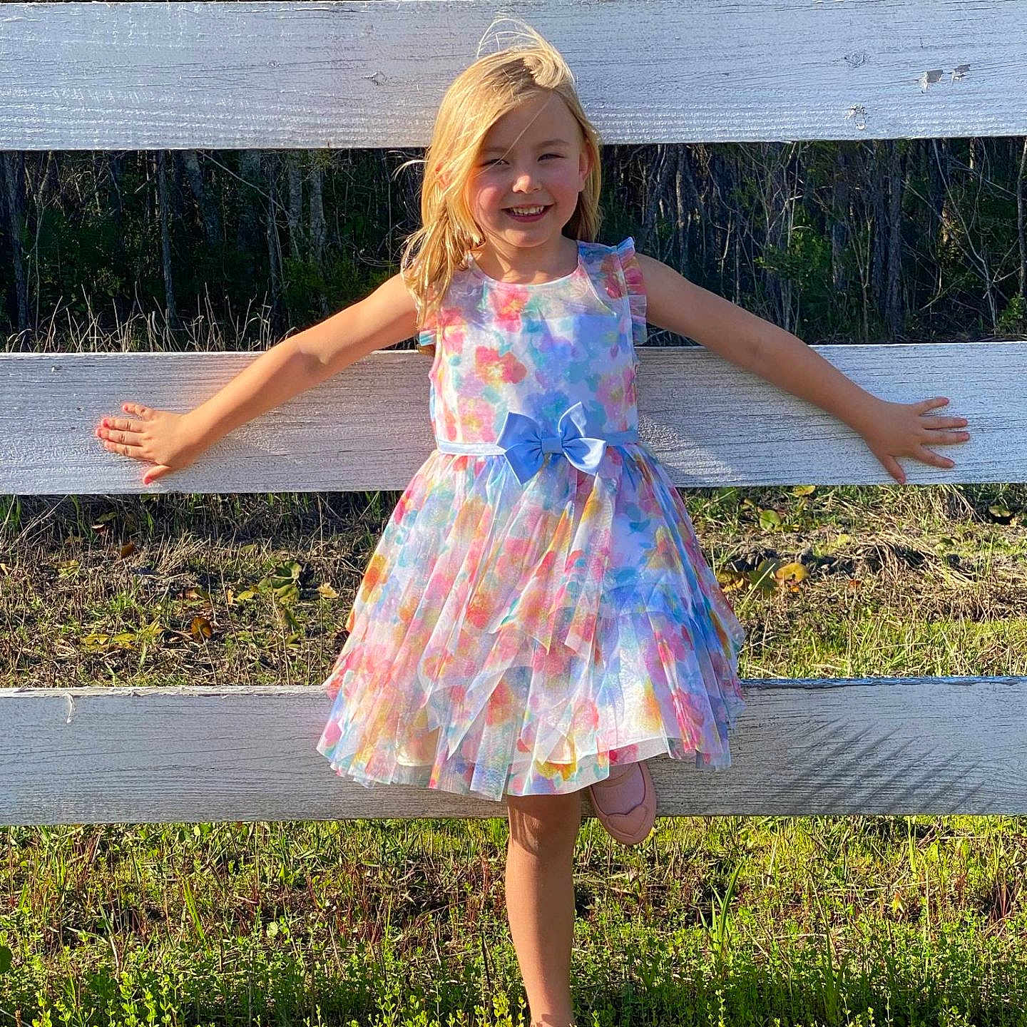 Emily is registered to the contest to win money with this photo: backyard, child, clothing, dress, face, female, girl, grass, happy, head, nature, outdoors, person, photography, picketfence, plant, portrait, sitting, sleeve, yard