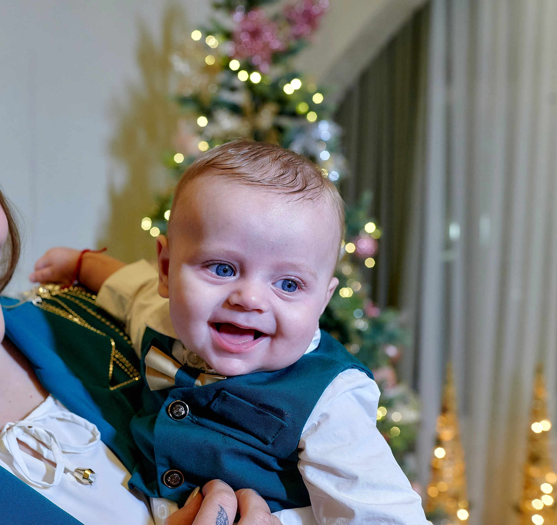 Stefan joined the competition — help win amazing prizes! baby, child, smiling, blue_eyes, vest, bowtie, celebration, christmas_tree, holiday, indoor, person, happy, festive, lights, portrait, cute, dressed_up, holding, infant, background_blur