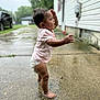 Maizie is registered to the contest to win money with this photo: toddler, child, barefoot, diaper, pink_shirt, wet_ground, side_view, curly_hair, outdoor, driveway, concrete, candid, water_droplets, exploring, summer, person, baby, standing, side_profile, residential_area