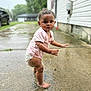 Maizie joined the competition — help win amazing prizes! toddler, child, barefoot, puddle, wet, outdoor, sidewalk, curly_hair, pink_shirt, diaper, concrete, residential, house, grass, blurred_background, daytime, expression, person, skin, water