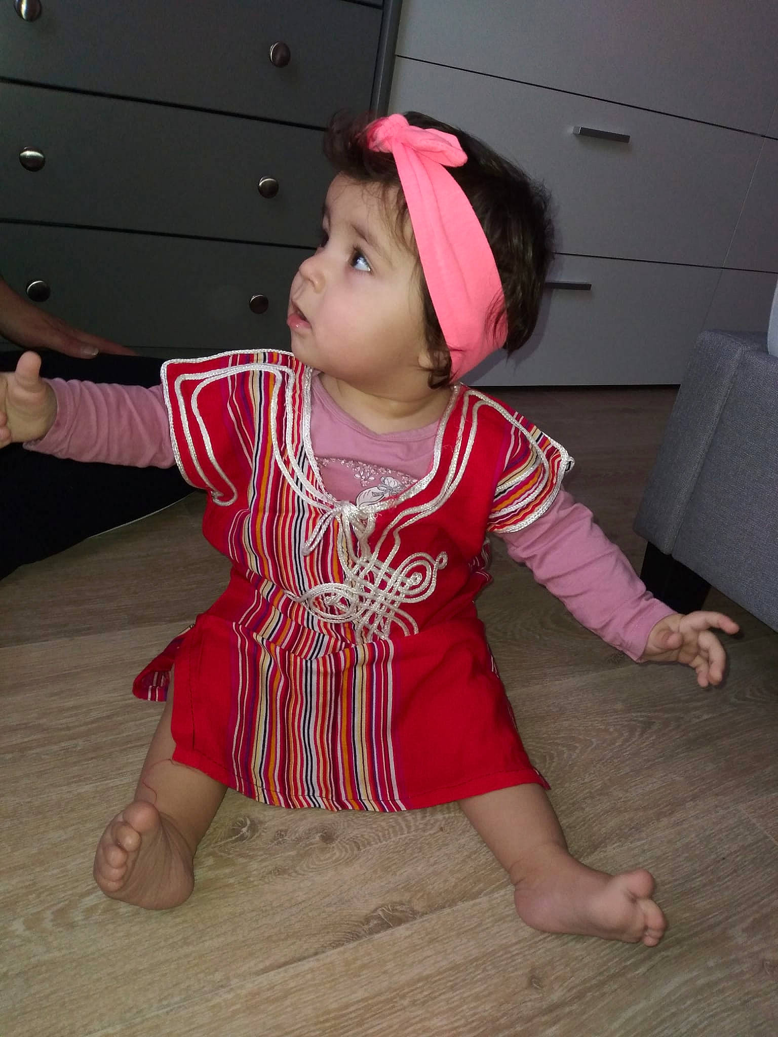 Safia participe au concours pour gagner de l'argent avec cette photo : baby, baby_toddler_clothing, barefoot, cheek, eye, flooring, foot, fun, happy, hardwood, hat, headwear, human_body, human_leg, magenta, person, pink, sitting, skin, sleeve