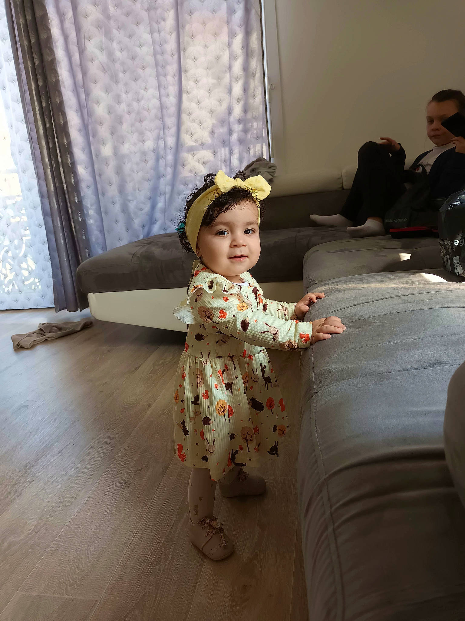 Safia a rejoint le concours — aidez-le/la à gagner de superbes lots ! child, comfort, curtain, dress, event, fashion_design, flash_photography, floor, flooring, formal_wear, fun, happy, hardwood, headwear, living_room, person, room, sandal, sitting, suit