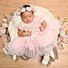 baby, baby_photography, basket, blanket, closed_eyes, fashion, floral_headband, flowers, indoor, infant, lying_down, peaceful, pink_dress, portrait, sleeping, soft_lighting, studio_photo, tulle_skirt, white_shoes, wood_floor