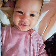 Victoria is registered to the contest to win money with this photo: baby, infant, child, smiling, portrait, face, eyes, pink_clothing, onesie, bed, blanket, bedding, bedroom, indoor, happy, cute, lying_down, close_up, photography, cozy