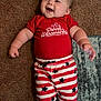 baby, child, smiling, red_shirt, striped_shorts, stars, carpet, rug, lying_down, happy, cute, infant, indoor, clothing, skin, face, hand, foot, person, young
