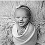 newborn, baby, smiling, headband, bow, blanket, wrapped, sleepy, cozy, soft_texture, black_and_white, portrait, infant, cute, peaceful, hands, face, resting, closeup, studio