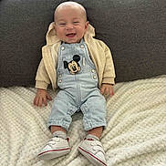 Maëlo participe au concours pour gagner de l'argent avec cette photo : baby, smiling, denim_overalls, mickey_mouse, hoodie, sitting, blanket, white_shoes, socks, couch, happy, infant, cute, clothing, indoor, portrait, child, funny_face, cozy, comfortable