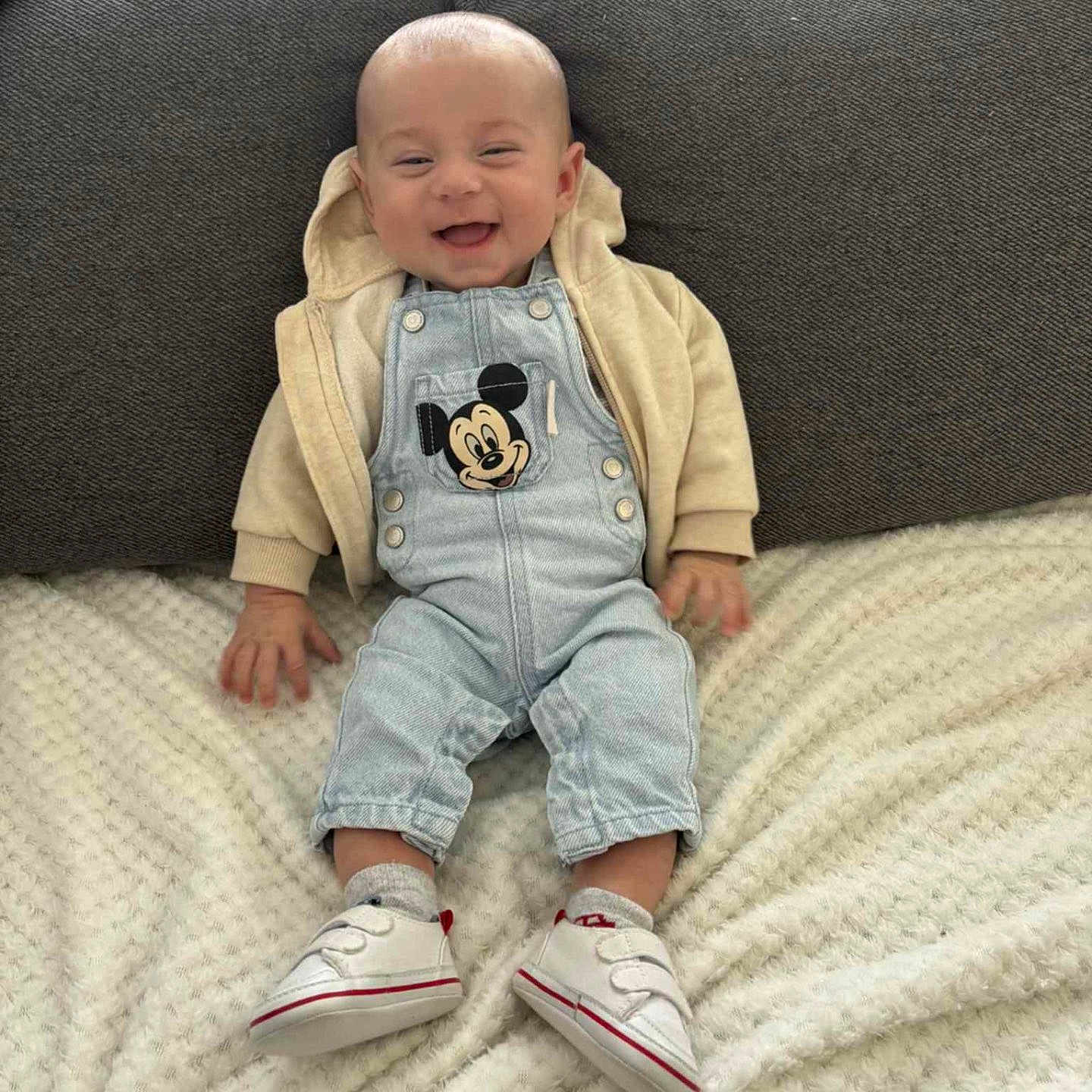 Maëlo participe au concours pour gagner de l'argent avec cette photo : baby, blanket, child, clothing, comfortable, couch, cozy, cute, denim_overalls, funny_face, happy, hoodie, indoor, infant, mickey_mouse, portrait, sitting, smiling, socks, white_shoes