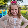 child, girl, blonde_hair, curly_hair, pink_bow, smile, outdoor, playground, grass, tree, necklace, casual_clothing, confident, happy, daylight, park, young, person, nature, portrait