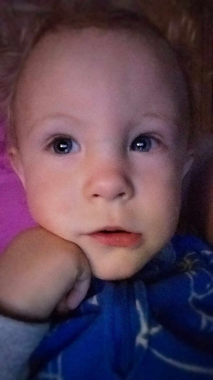 Rollin is registered to the contest to win money with this photo: toddler, child, close_up, face, hand, blue_clothing, curious_eyes, indoor, soft_lighting, portrait, young_child, resting_chin, expression, skin, eyelashes, nose, mouth, casual, cozy, intimate