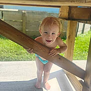 Rollin is registered to the contest to win money with this photo: child, toddler, smiling, barefoot, wood, outdoor, sunlight, playful, diaper, greenery, fence, patio, beam, shadow, happy, person, summer, daylight, nature, cute