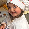 blue_bowl, chef_hat, child, colorful, cute, girl, happy, holding, indoors, kitchen, long_hair, orange_stripes, person, play, portrait, pretend_play, shelf, smiling, toy_food, white_jacket