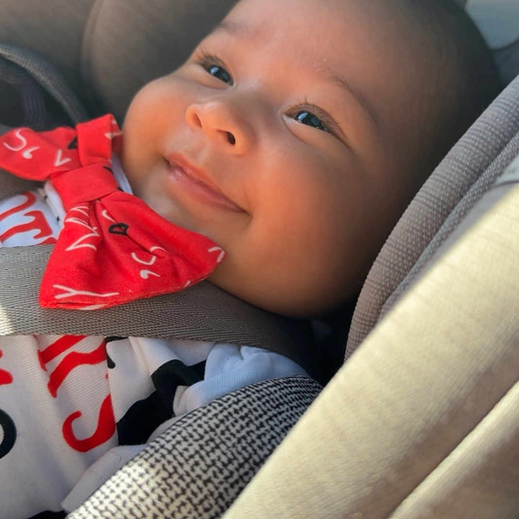 Jaxxon joined the competition — help win amazing prizes! baby, baby_clothes, car_interior, car_seat, child, closeup, clothing, cute, face, happy, indoor, infant, portrait, red_bow_tie, safety, seat, seatbelt, smiling, toddler, young_child