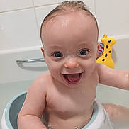 Noah is registered to the contest to win money with this photo: baby, bath, water, smile, happy, toy, giraffe, bathtub, child, sitting, skin, face, eyes, arm, head, bathroom, wet, cute, joy, infant