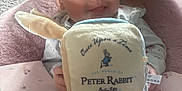 Jaime is registered to the contest to win money with this photo: baby, book, carpet, child, clothing, comfort, cute, face, indoor, infant, mirror, person, peter_rabbit, pink_cushion, plush_toy, reflection, seated, smile, soft_toy, toy