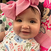 Leah is registered to the contest to win money with this photo: baby, child, pink_bow, smiling, face, flower_pattern, clothing, seat, minnie_mouse, cartoon, headband, cute, infant, portrait, closeup, happy, indoor, person, baby_girl, colorful