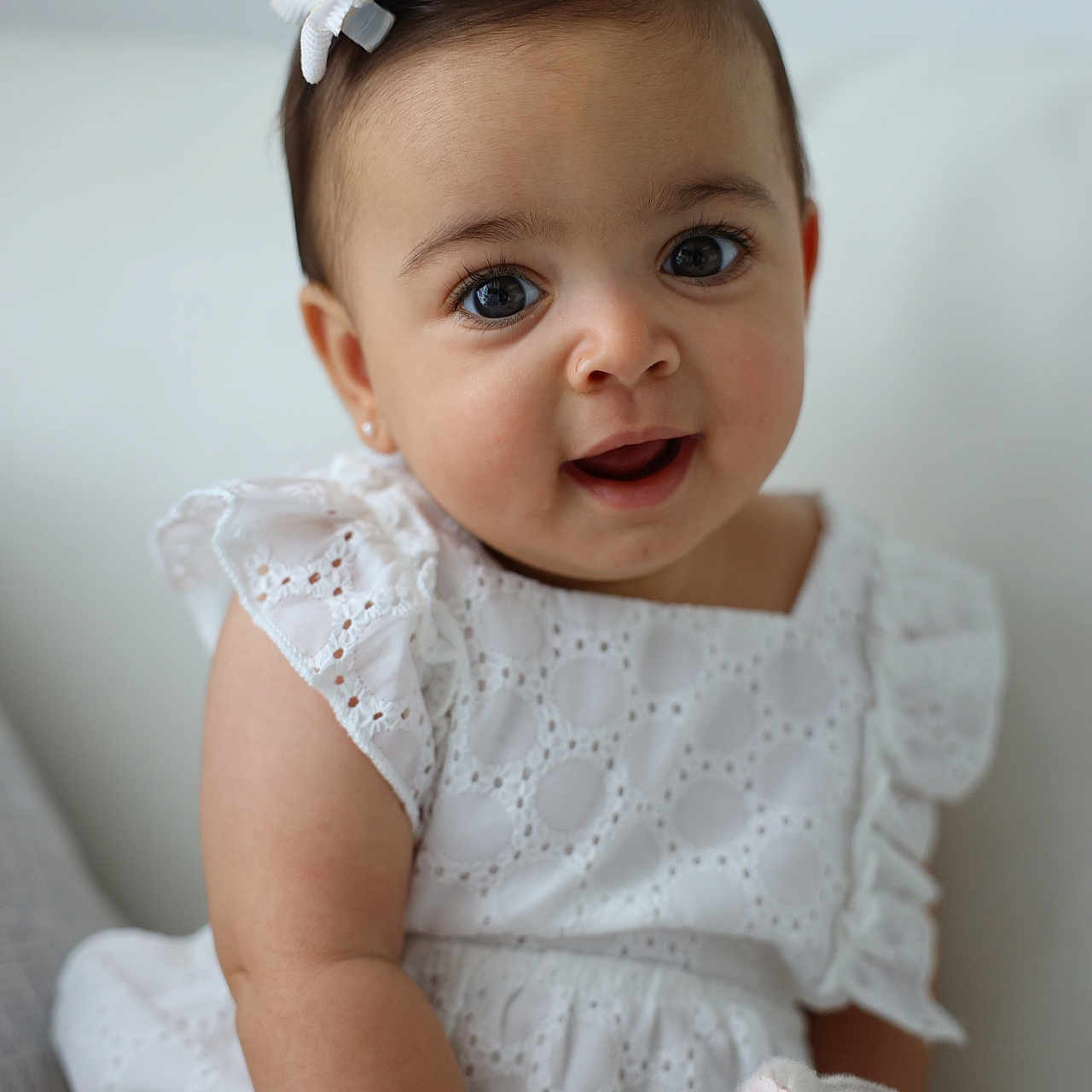 Miana is registered to the contest to win money with this photo: arm, baby, bow, child, closeup, cute, eyelashes, face, girl, happy, indoors, infant, plush_toy, portrait, sitting, skin, smiling, soft_toy, stuffed_animal, white_dress