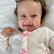 Ashley is registered to the contest to win money with this photo: baby, smiling, blue_eyes, headband, pink_bows, white_outfit, infant, cute, happy, lying_down, blanket, pattern, hummingbird, soft_texture, portrait, child, clothing, indoor, closeup, adorable