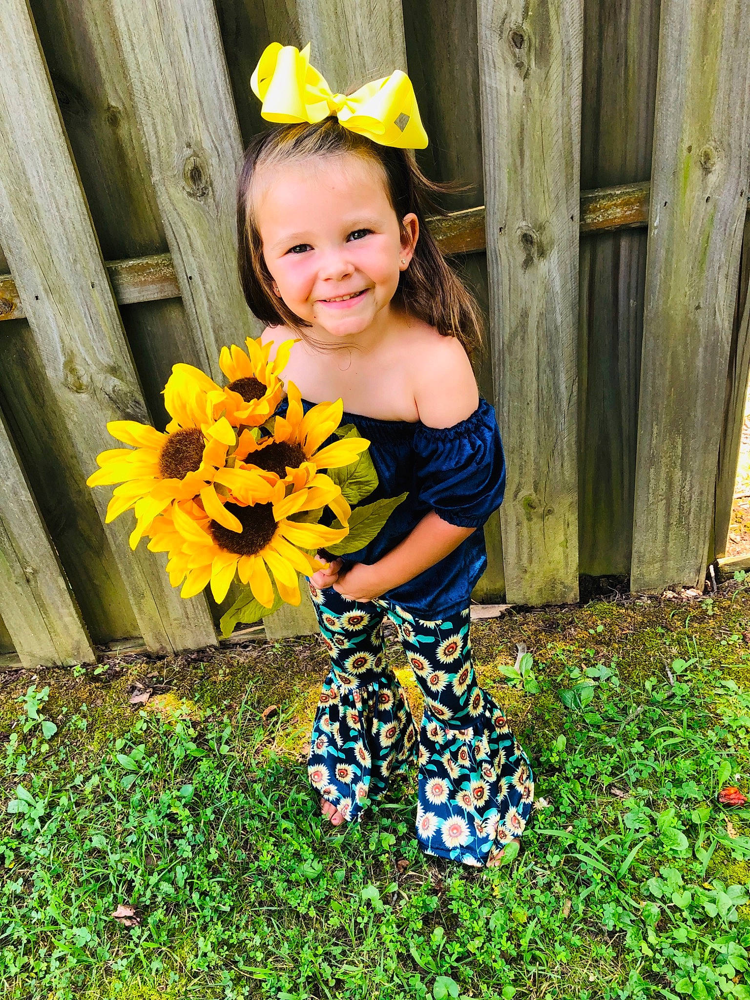 Pearl is registered to the contest to win money with this photo: baby_toddler_clothing, child, child_model, costume, dress, flower, happy, joy, pattern, person, plant, smile, spring, sunflower, toddler, wildflower, yellow