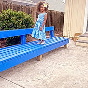 Adi Sera is registered to the contest to win money with this photo: child, girl, blue_dress, flower, curly_hair, bench, outdoor, backyard, fence, house, concrete, smile, standing, plant, shoes, daylight, sidewalk, portrait, happy, casual