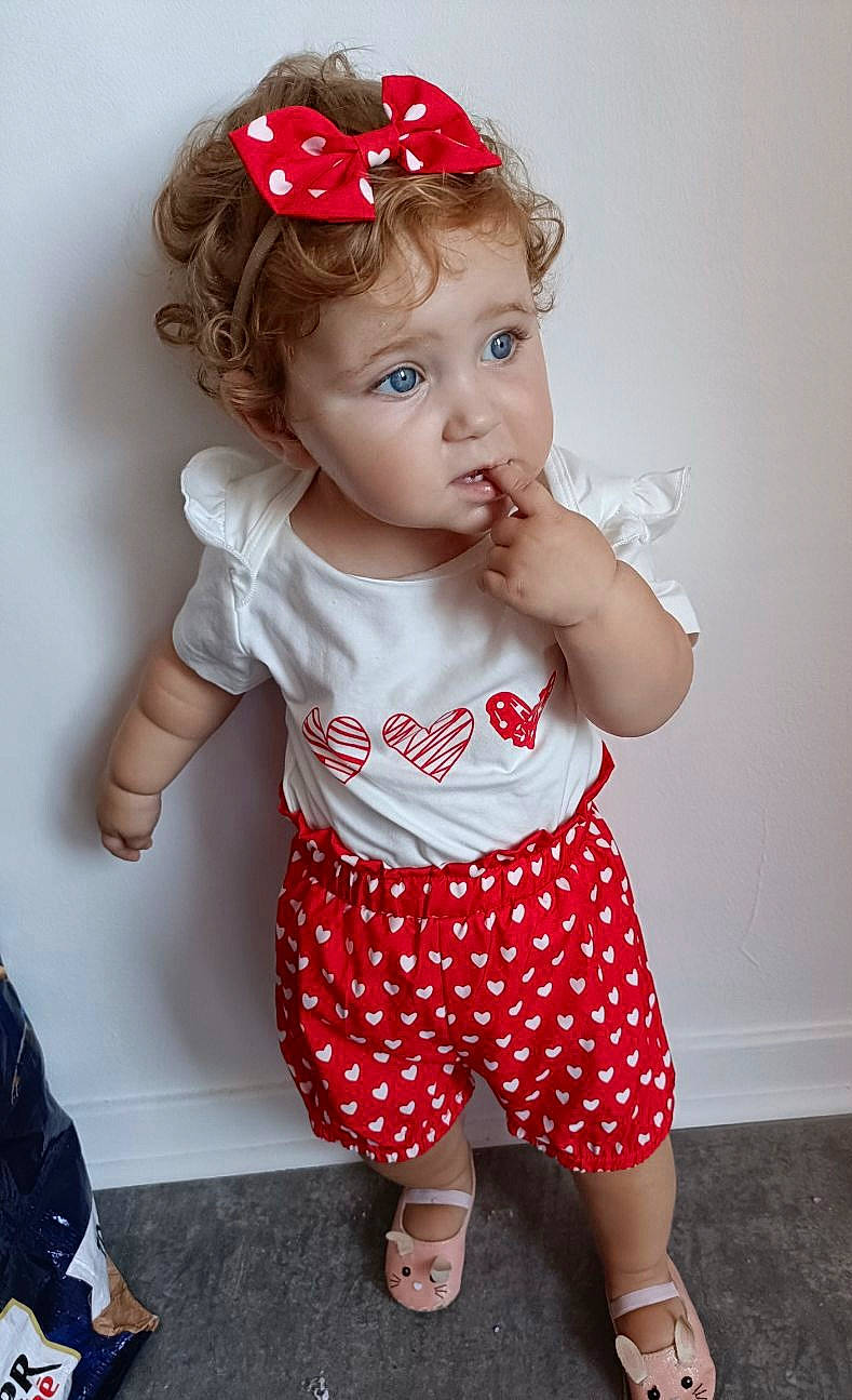 Coraline participe au concours pour gagner de l'argent avec cette photo : baby, baby_toddler_clothing, child, hairstyle, head, headpiece, human_leg, knee, lip, pattern, person, pink, product, red, shorts, skin, sleeve, thigh, toddler, waist