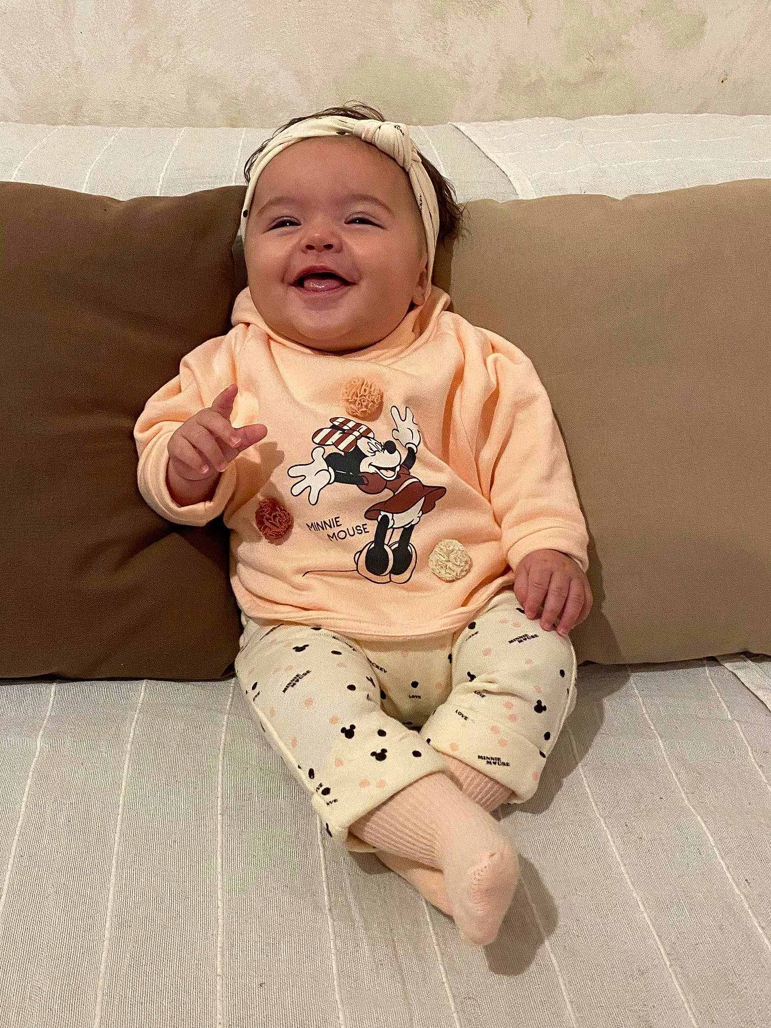 Maïly participe au concours pour gagner de l'argent avec cette photo : baby, baby_toddler_clothing, barefoot, beige, cheek, child, comfort, couch, face, foot, headband, headwear, human, living_room, mouth, nightwear, nose, person, skin, sleeve