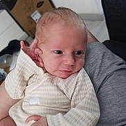 Ewen participe au concours pour gagner de l'argent avec cette photo : baby, newborn, infant, person, clothing, striped_onesie, hand, face, eyes, indoor, adult_arm, holding, curious, skin, head, expression, soft_lighting, furniture, blurred_background, cozy