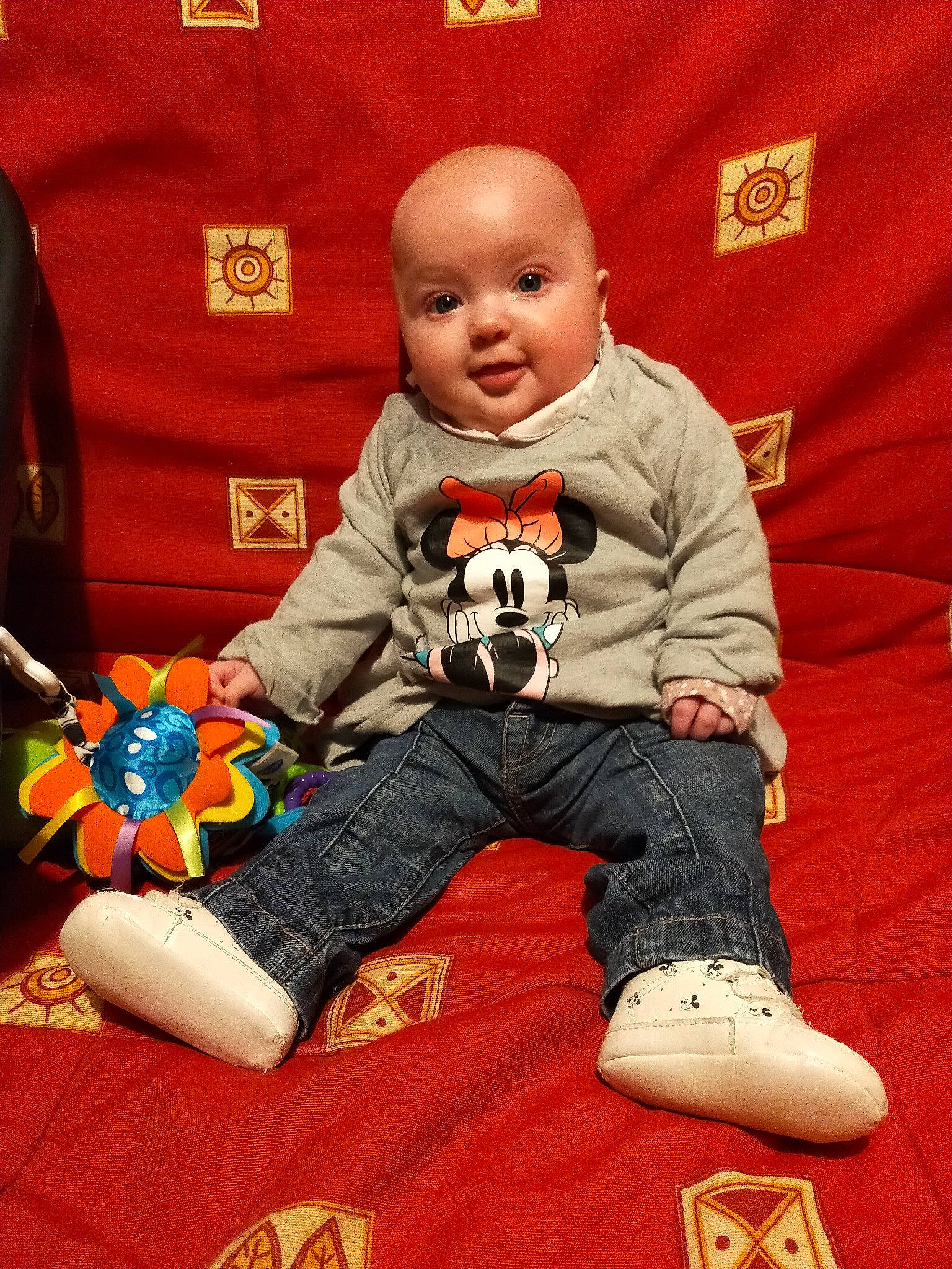 Lyana a rejoint le concours — aidez-le/la à gagner de superbes lots ! baby, baby_toddler_clothing, carmine, carpet, child, comfort, flooring, fun, happy, orange, pattern, person, play, red, room, sitting, sleeve, smile, t_shirt, toddler