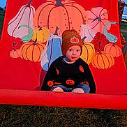 Luca is registered to the contest to win money with this photo: toddler, child, pumpkin, beanie, sweater, autumn, fall, outdoor, grass, illustration, red_backdrop, seasonal, cute, portrait, clothing, young_child, festive, holiday, pumpkin_pattern, casual