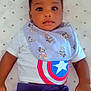 baby, child, toddler, infant, mickey_mouse, bib, tshirt, captain_america, polka_dot, bedspread, clothing, face, hands, lying_down, portrait, cute, indoor, young_child, casual_wear, baby_girl_or_boy