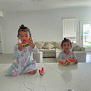 Giorgina is registered to the contest to win money with this photo: child, toddler, watermelon, kitchen, counter, pajamas, food, indoor, living_room, sofa, window, door, curly_hair, person, snack, fruit, table, light, home, cute