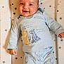 baby, infant, smile, face, pajamas, winnie_the_pooh, clothing, pattern, stars, cushion, lying_down, child, cute, happy, indoor, portrait, person, soft_lighting, blue, sleepwear