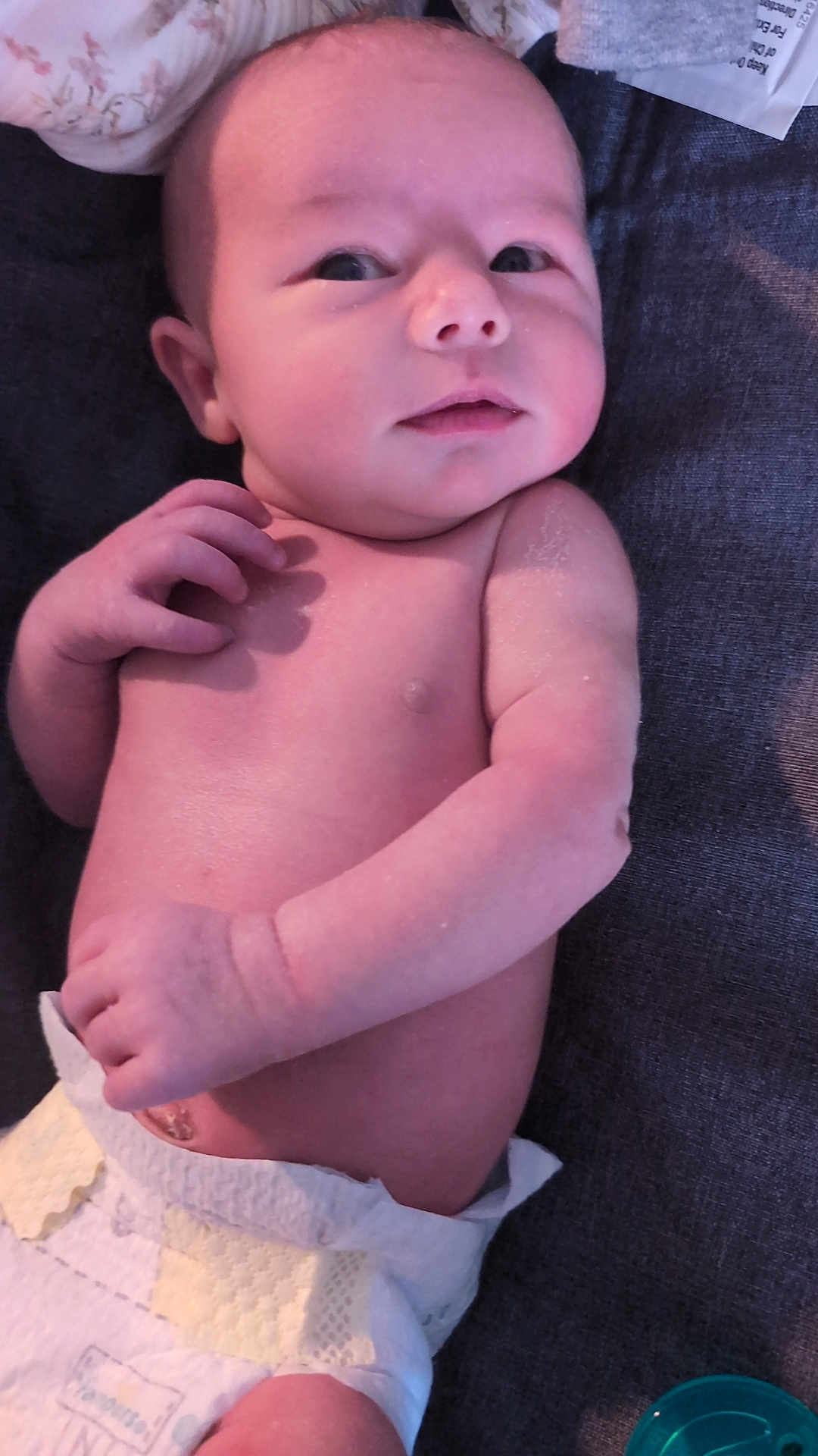 Reina is registered to the contest to win money with this photo: baby, infant, newborn, diaper, lying_down, skin, face, hand, pacifier, expression, curious, fabric, texture, closeup, human, child, soft_lighting, pale_skin, portrait, indoors