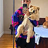 person, dog, pet, mirror_selfie, fluffy, furry, chow_chow, portrait, indoors, bedroom, bed, teddy_bear, sportswear, jersey, phone, smartphone, reflection, standing, wood_floor, cute