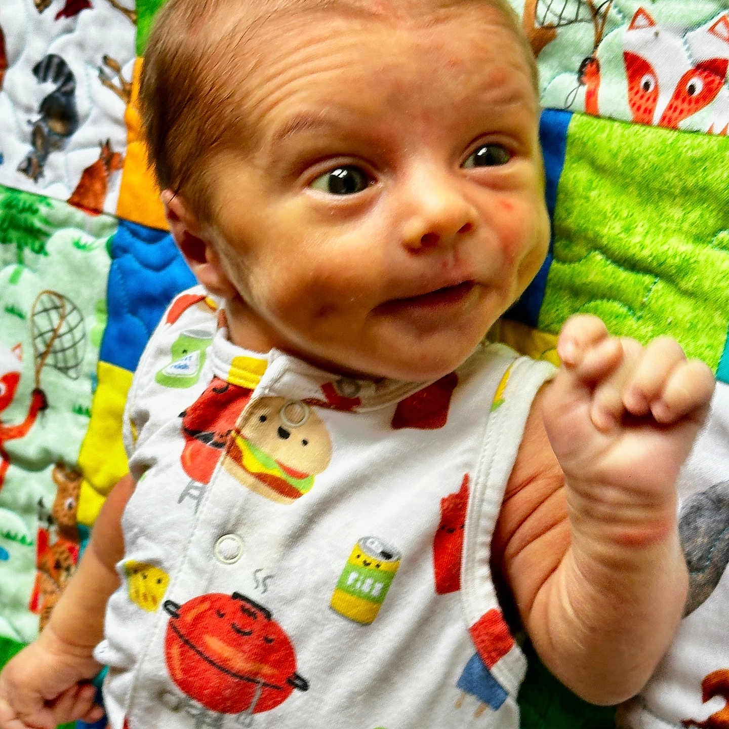 Jaxon is registered to the contest to win money with this photo: applique, baby, blanket, bodypart, clothing, cutlery, face, finger, furniture, hand, happy, head, newborn, pattern, person, photography, portrait, quilt, smile, t_shirt