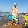 child, boy, beach, sand, water, bucket, shovel, summer, sunny, cap, shorts, barefoot, sea, ocean, play, fun, holiday, coast, shore, waves