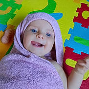 Idyle participe au concours pour gagner de l'argent avec cette photo : baby, blue_eyes, bright_colors, child, colorful_mat, cute, foam_puzzle, hand, happy, head, indoors, infant, lying_down, playful, skin, smiling, soft_texture, tongue_out, towel, wrapped