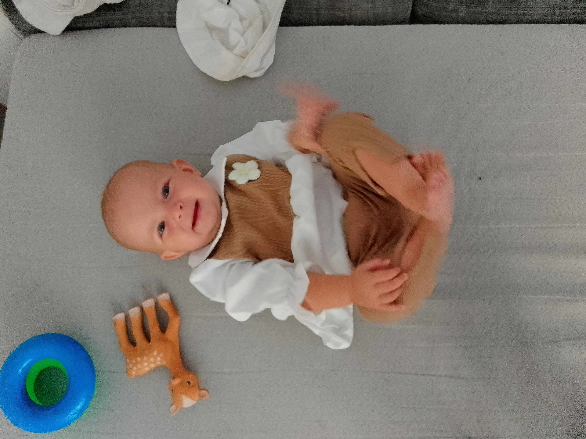 Idyle participe au concours pour gagner de l'argent avec cette photo : baby, child, smiling, toy, giraffe_toy, blue_ring, clothing, brown_outfit, white_shirt, face, hand, foot, lying_down, soft_surface, couch, indoor, cute, playful, infant, happy