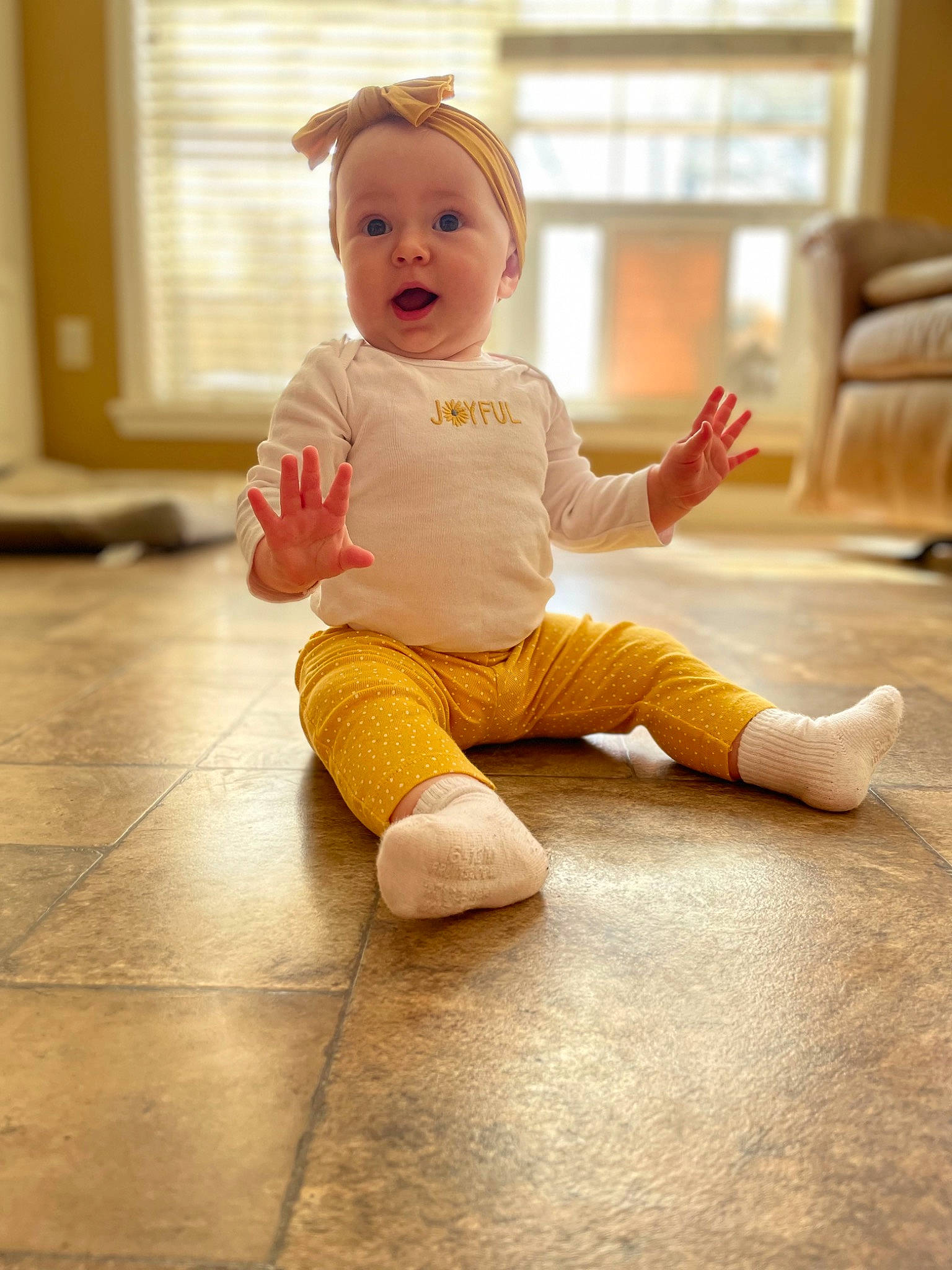 Adelynn is registered to the contest to win money with this photo: baby, baby_toddler_clothing, barefoot, cheek, face, floor, flooring, foot, happy, hardwood, human_leg, joint, knee, leg, person, skin, sleeve, surprise, thigh, toddler