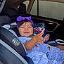 Nazneen is registered to the contest to win money with this photo: toddler, child, car_seat, purple_headband, white_dress, embroidery, car_interior, window, seatbelt, bottled_water, playful, smiling, person, young_child, baby, seat, safety, happy, cute, indoors