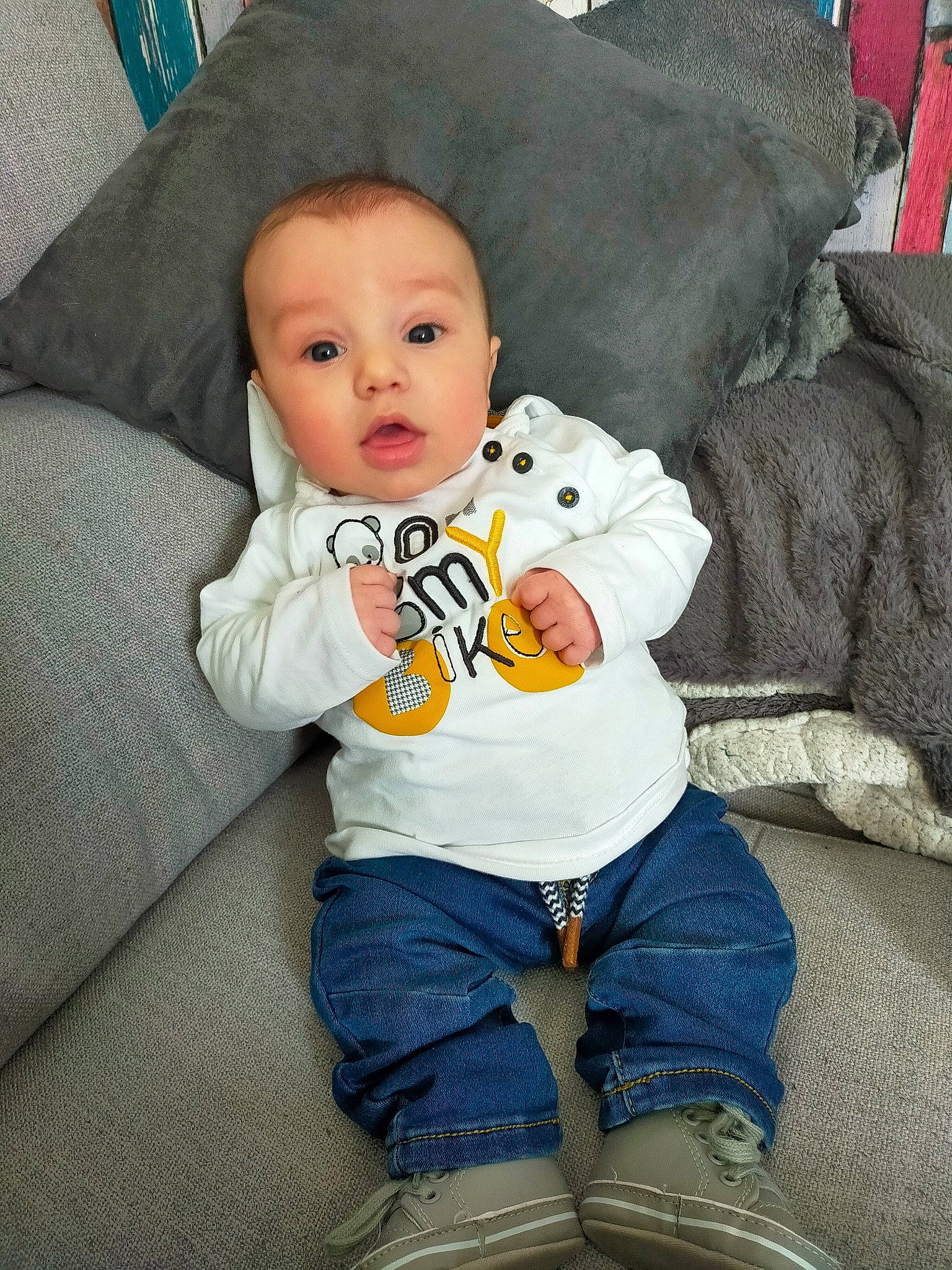 Liam a rejoint le concours — aidez-le/la à gagner de superbes lots ! baby, baby_toddler_clothing, blue, cheek, child, clothing, comfort, couch, denim, eye, iris, jeans, lap, linens, nose, person, sitting, skin, sleeve, surprise