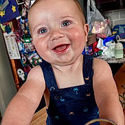 Bode is registered to the contest to win money with this photo: arms, baby, blue_eyes, child, cluttered, crab_print, cute, happy, indoor, infant, kitchen, magnets, navy_romper, notes, palm_tree_print, person, portrait, refrigerator, smiling, table