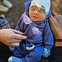 baby, sleeping, blue_outfit, hat, hands, striped_socks, infant, cozy, closeup, outdoor, natural_light, blurred_background, person, child, newborn, cute, soft_texture, resting, tiny_clothes, portrait