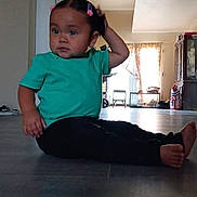 Everly joined the competition — help win amazing prizes! toddler, child, indoor, floor, green_shirt, black_pants, hair_clips, curious, sitting, scratching_head, home, window, natural_light, wood_floor, cabinet, shoes, curtains, chair, person, casual