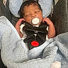 newborn, baby, pacifier, car_seat, blanket, sleeping, child, infant, hands, clothing, fabric, head_support, safety_harness, indoor, person, portrait, cozy, cute, resting, closeup