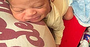 Apharri joined the competition — help win amazing prizes! newborn, baby, pillow, blanket, infant, sleeping, resting, hand, red_clothing, water_bottle, curly_hair, indoors, soft_texture, peaceful, closeup, person, candid, comfort, head, skin