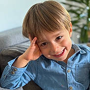 Darren participe au concours pour gagner de l'argent avec cette photo : child, boy, smile, blue_shirt, couch, indoor, portrait, happy, casual, face, young, person, blond_hair, button_up, relaxed, home, furniture, plant, background_blur, cheerful
