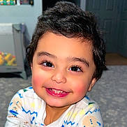 Sultan is registered to the contest to win money with this photo: baby, child, cozy, cute, expression, eyes, face, floor, hair, happy, indoors, infant, pajamas, person, playroom, portrait, rosy_cheeks, smile, toddler, warm_lighting