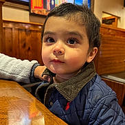 Sultan joined the competition — help win amazing prizes! baby, casual, child, clothing, corduroy_collar, curious, cute, face, indoor, jacket, long_eyelashes, looking_away, painting, person, portrait, restaurant, seated, toddler, warm_lighting, wooden_table